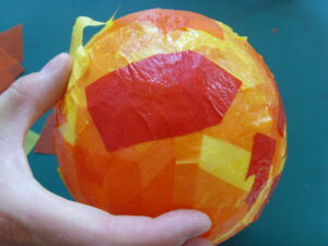 Ajout de papier de soie rouge sur le lampion en cours de création