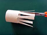 Découpe de bandes régulières aux ciseaux dans un rouleau de papier toilette pour faire les pattes de l'araignée.