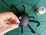 Collage des yeux mobiles en plastique sur la tête de l'araignée noire.